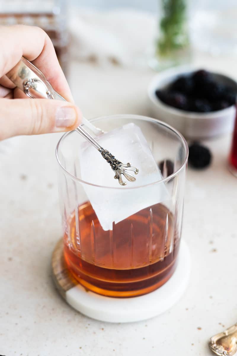 A large ice cube being added to the glass. 