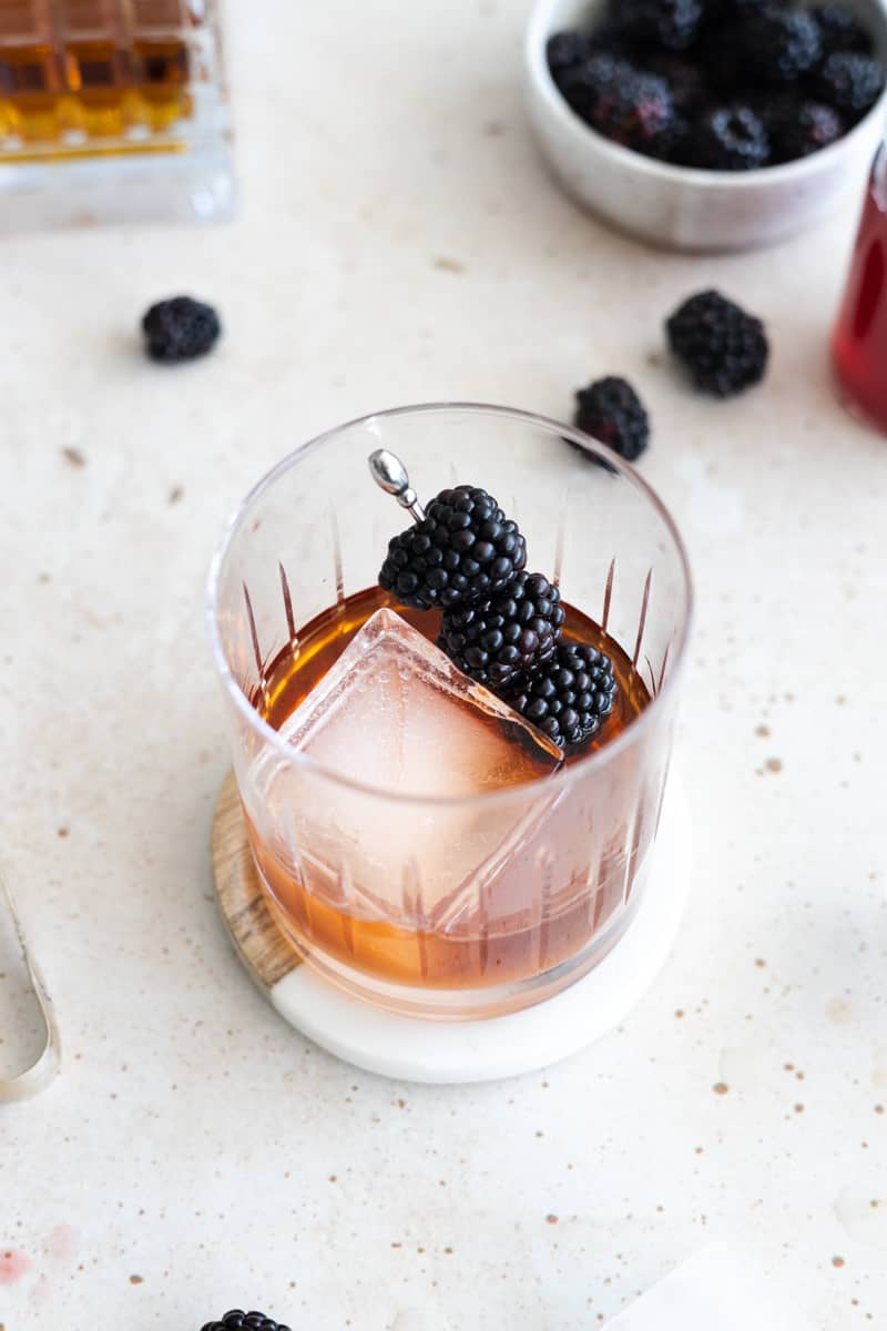Blackberries on a cocktail pick added to the glass. 