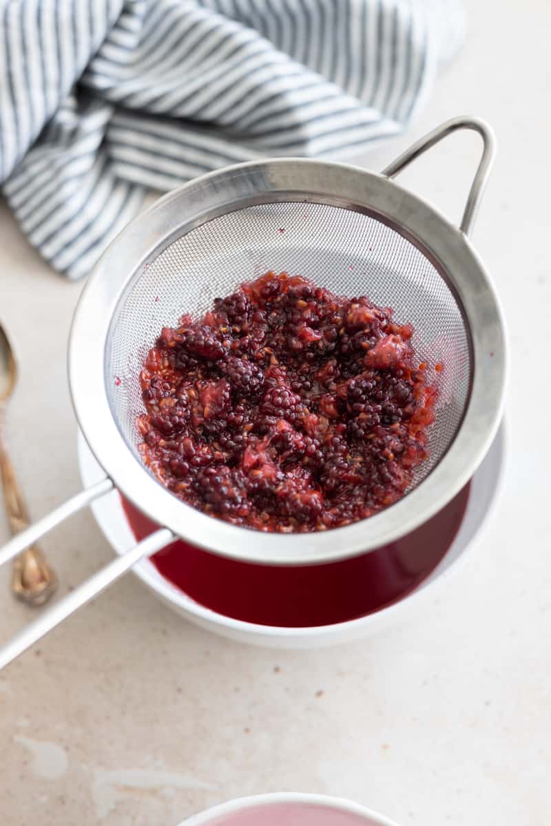 Blackberry simple syrup being strained to remove the extra seeds and pulp from the liquid. 