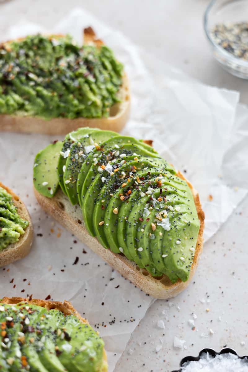 A closeup of avocado toast with everything bagel seasoning sprinkled on top. 
