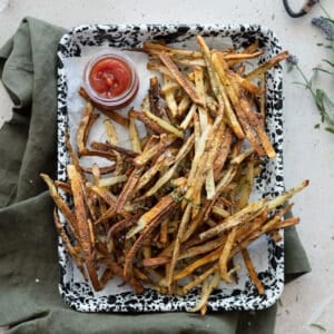 Garlic rosemary fries on a tray with a small bowl of ketchup.