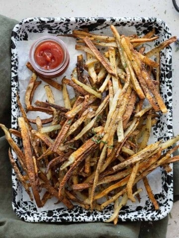 Garlic rosemary fries on a tray with a small bowl of ketchup.