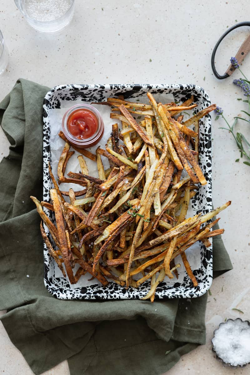 A tray of garlic rosemary fries with a small bowl of ketchup. 