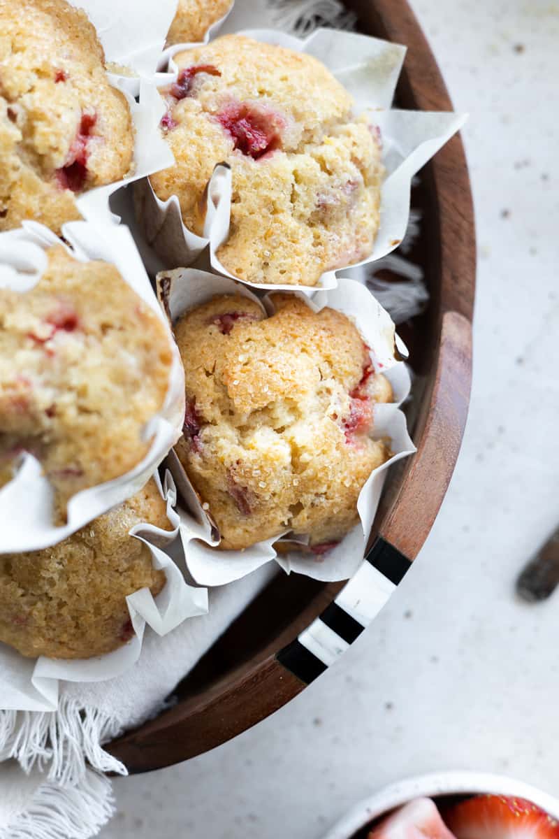 A closeup of Strawberry Rhubarb Muffins on a wooden tray. 