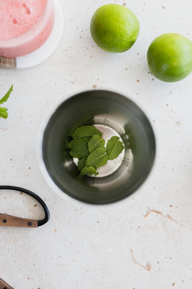 Mint leaves in the bottom of a cocktail shaker. 