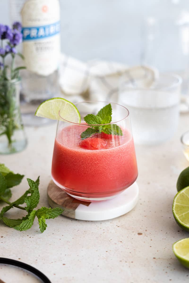 Watermelon mint cocktail in a rocks glass garnished with a lime slice and mint sprig. 