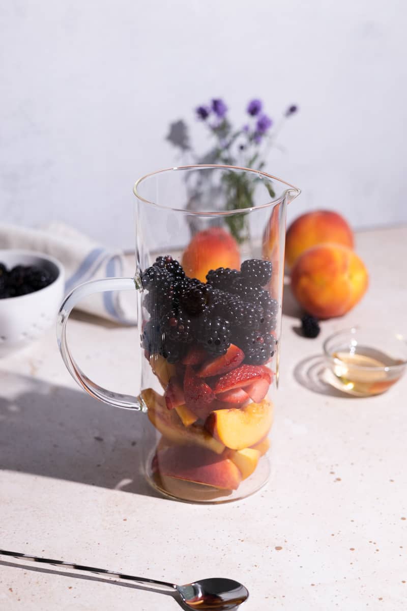 Sliced fruits in a glass pitcher.