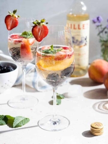 Simple white sangria in wine glasses with fresh fruit.