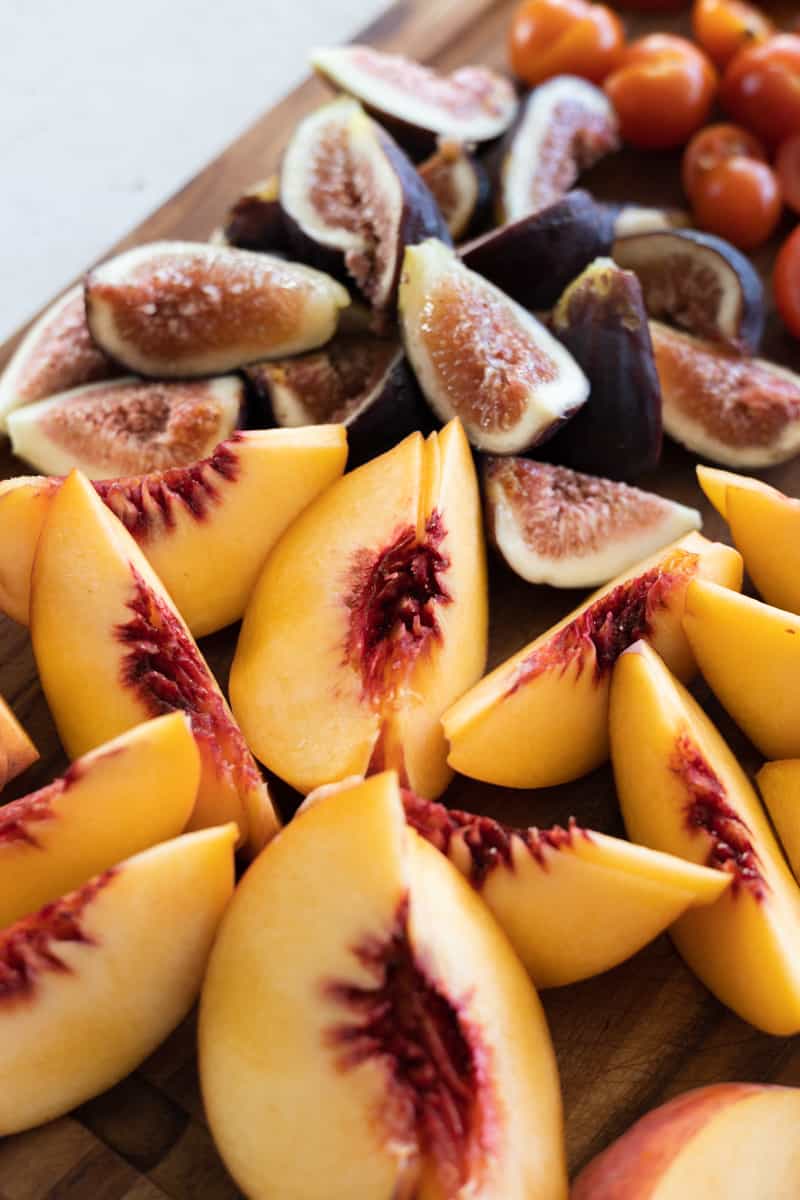 Sliced peaches and figs on a wooden cutting board.