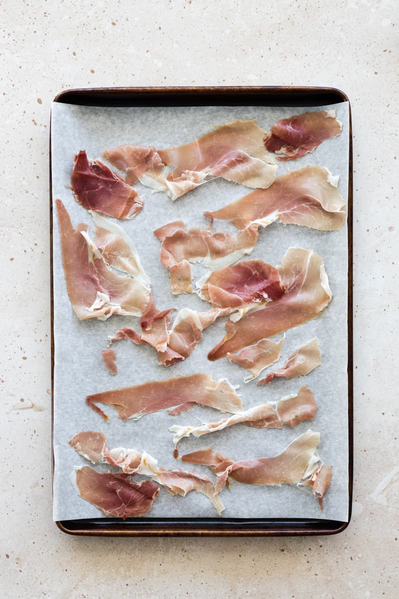Prosciutto on a parchment paper-lined baking sheet.
