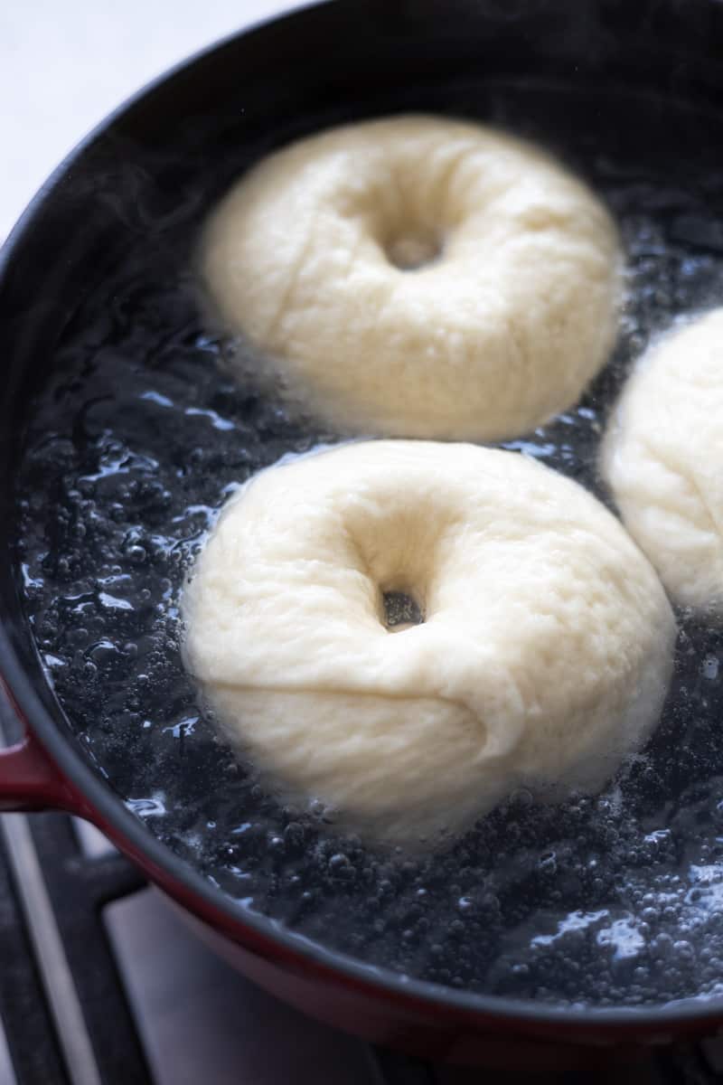 3 bagels boiling in a pot of water. 