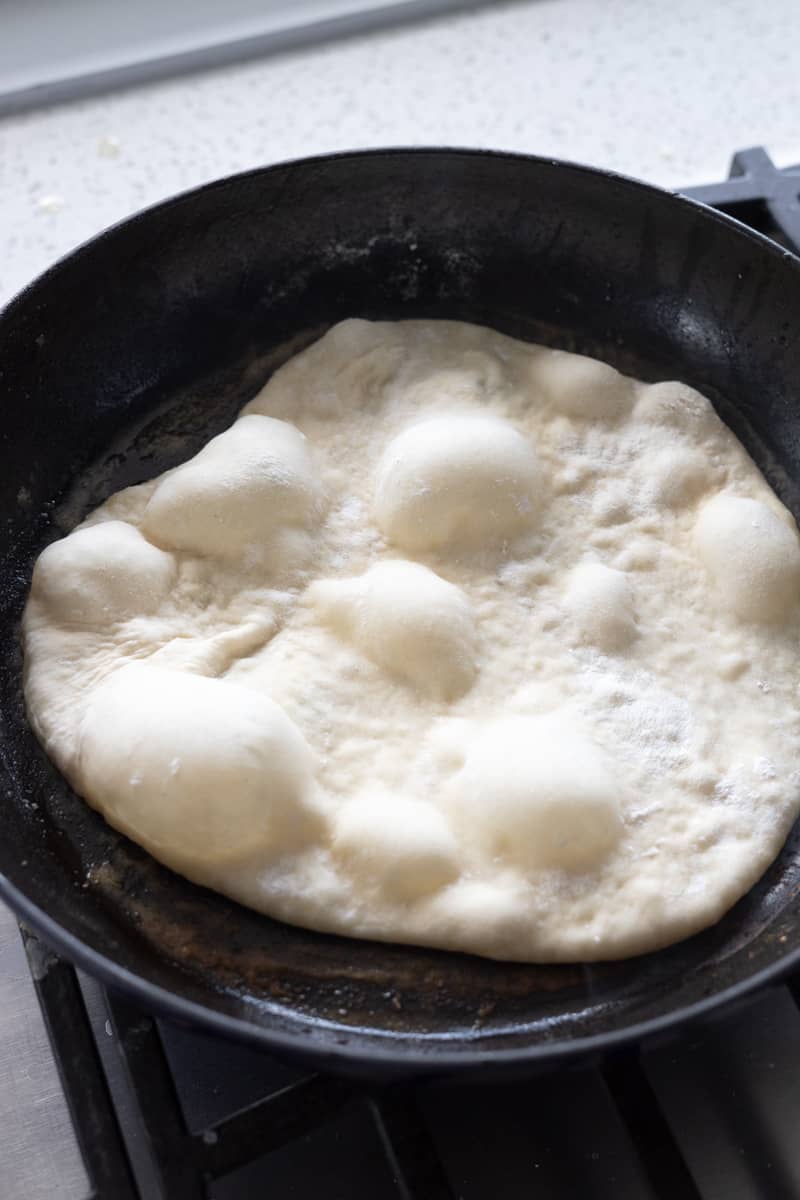 Bubbling dough cooking in a cast iron skillet. 