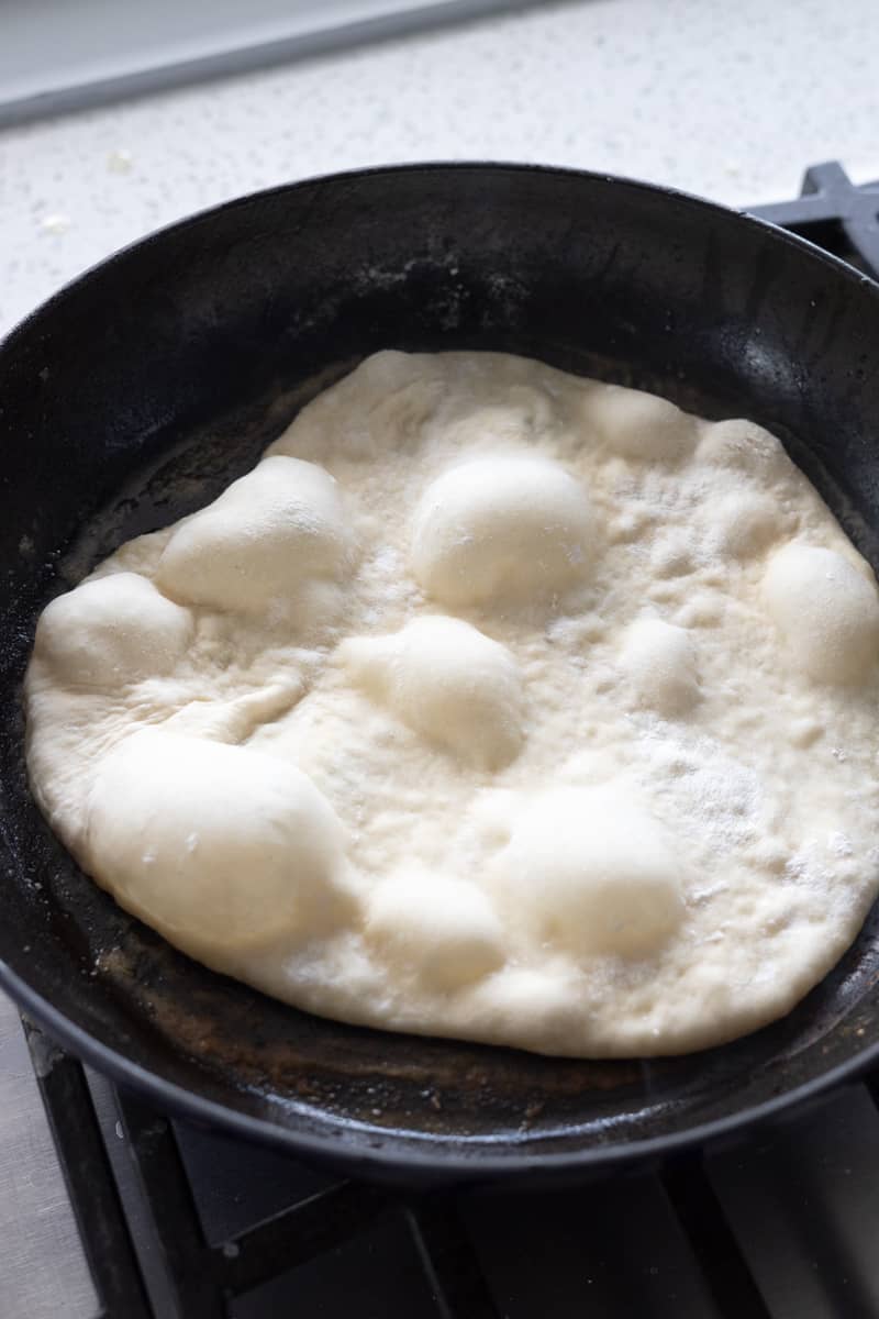 Bubbling dough cooking in a cast iron skillet.