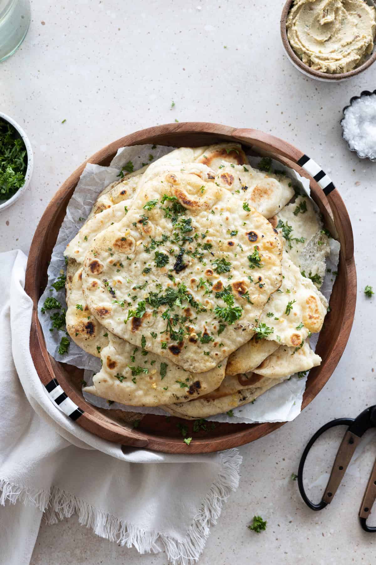 A pile of Sourdough Discard Naan on a wooden tray.