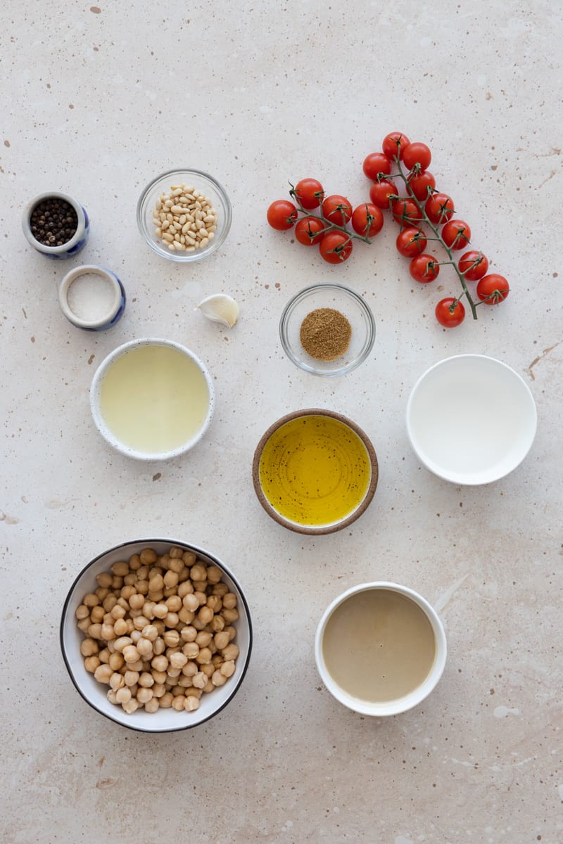 Ingredients for hummus with roasted vine tomatoes in small bowls. 