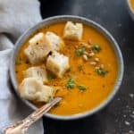 Pumpkin and Carrot Soup in a grey bowl with croutons.
