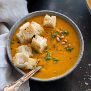 Pumpkin and Carrot Soup in a grey bowl with croutons.