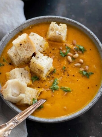 Pumpkin and Carrot Soup in a grey bowl with croutons.