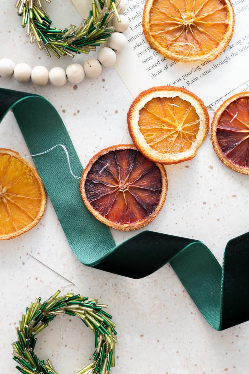 Oranges strung together to make a garland next to a green ribbon. 