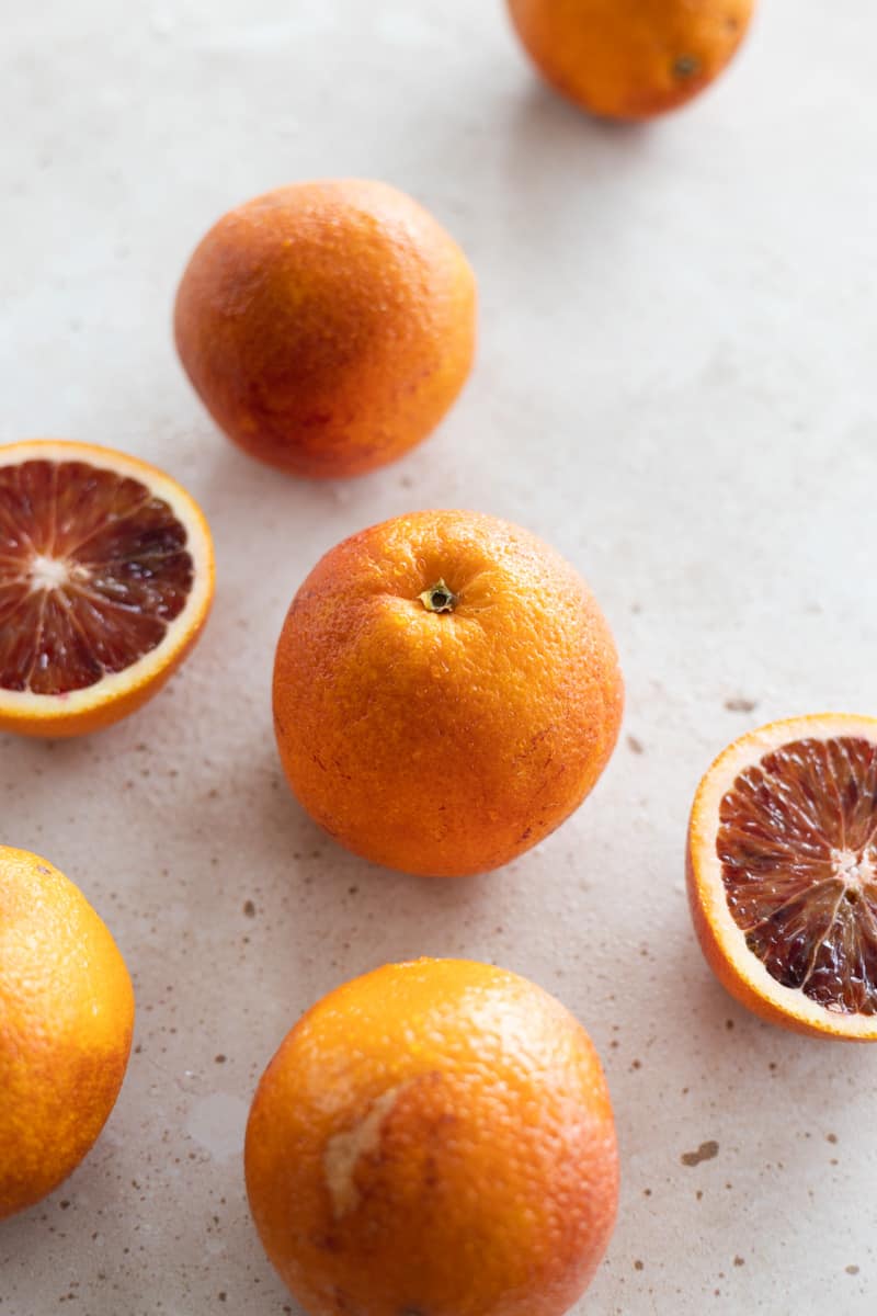 Whole and halved blood oranges on the countertop. 