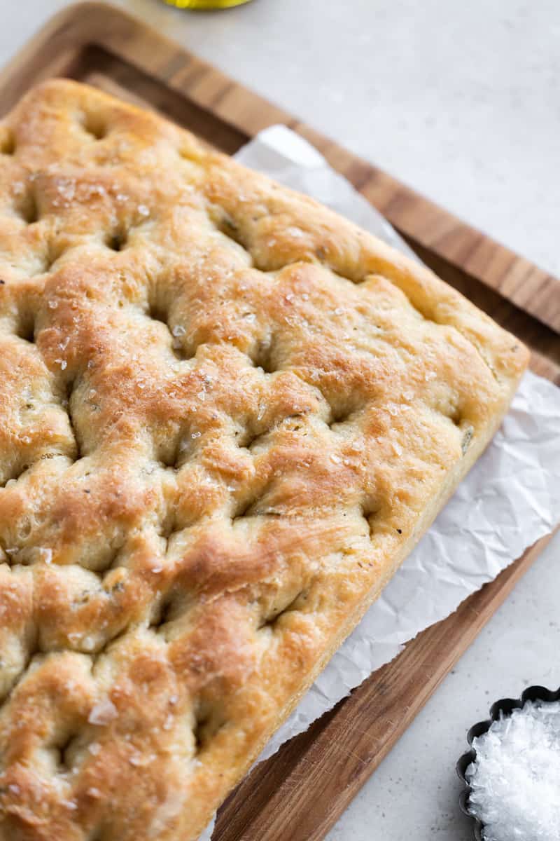 Baked focaccia on a wooden cutting board. 