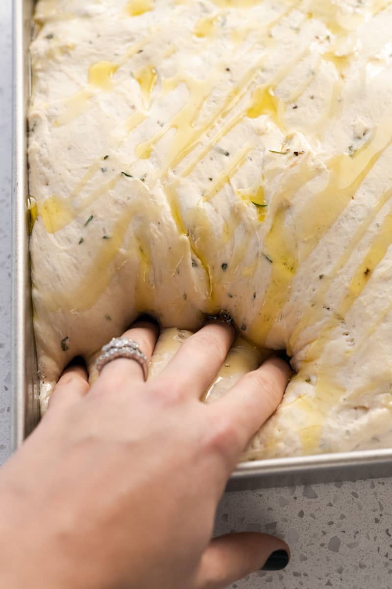 Fingers pressing dimples into the dough. 