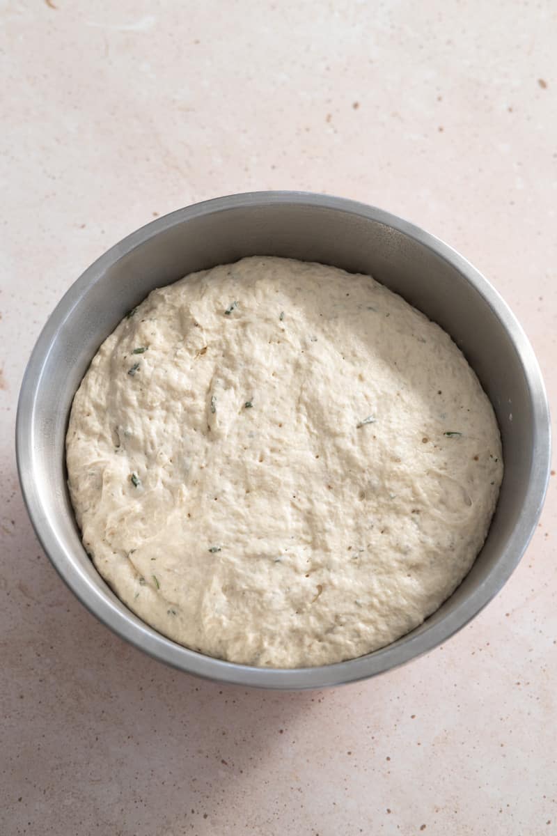 Dough in a large metal bowl after the first rise. 