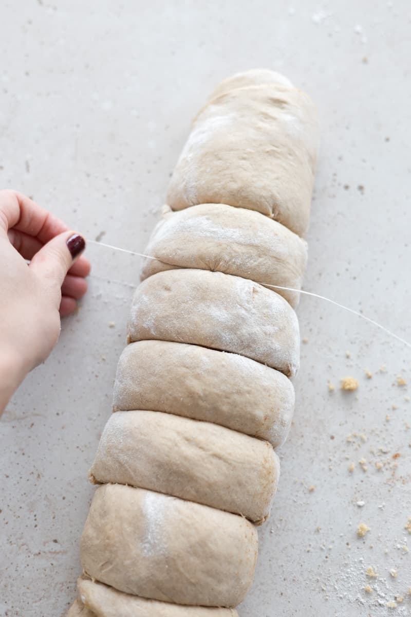 Rolled dough being cut with dental floss. 