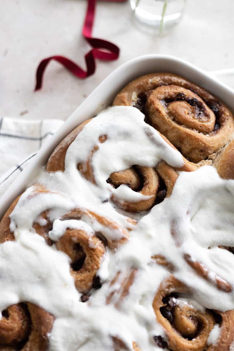 Rolls in a white baking dish spread with white icing.