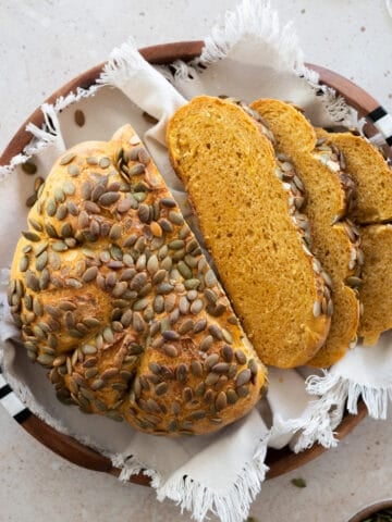 Sliced sourdough pumpkin bread on a wooden tray with white linen.