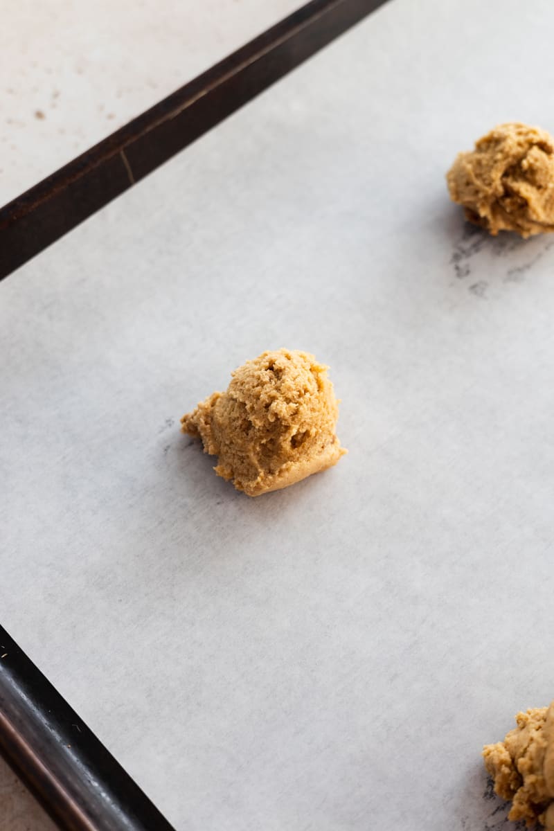 Cookie dough on a parchment paper-lined baking sheet. 