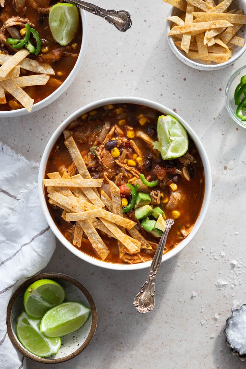 Healthy hicken tortilla soup in a white bowl with a spoon.