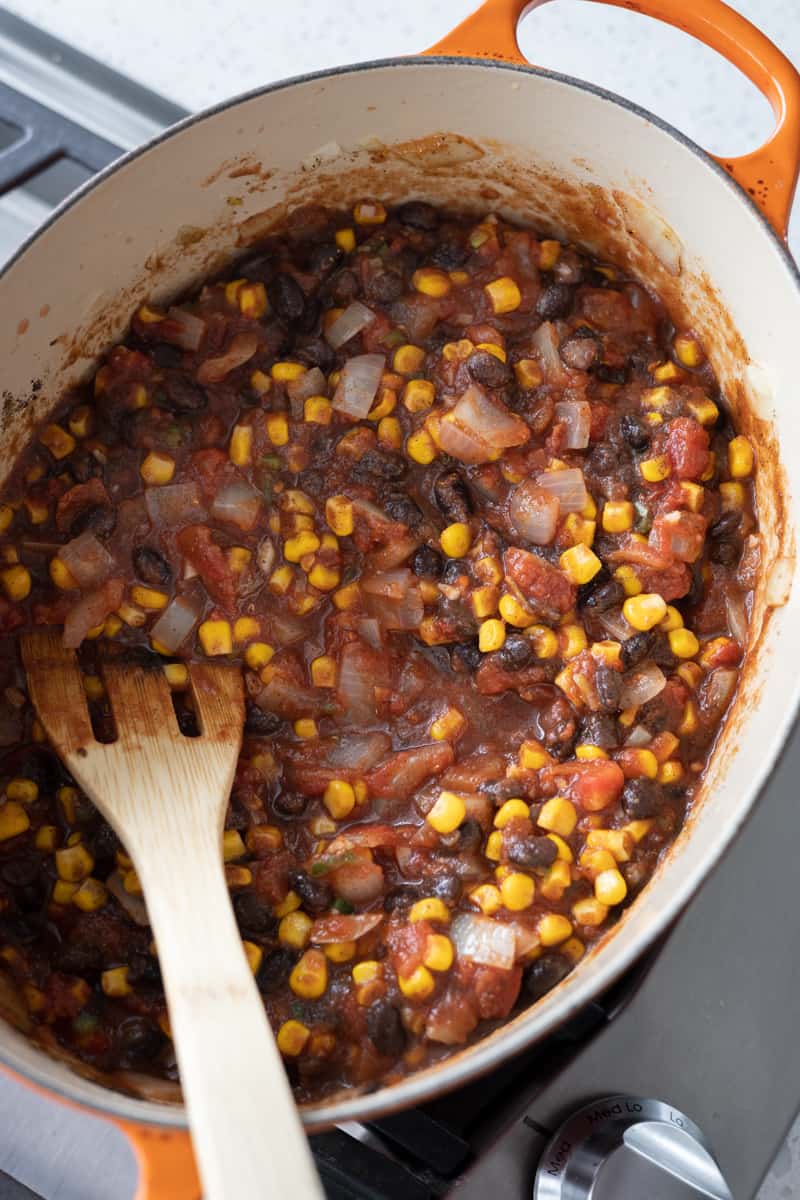 Jalapeño, tomatoes, corn, black beans, tomato paste and spices added to the Dutch oven.