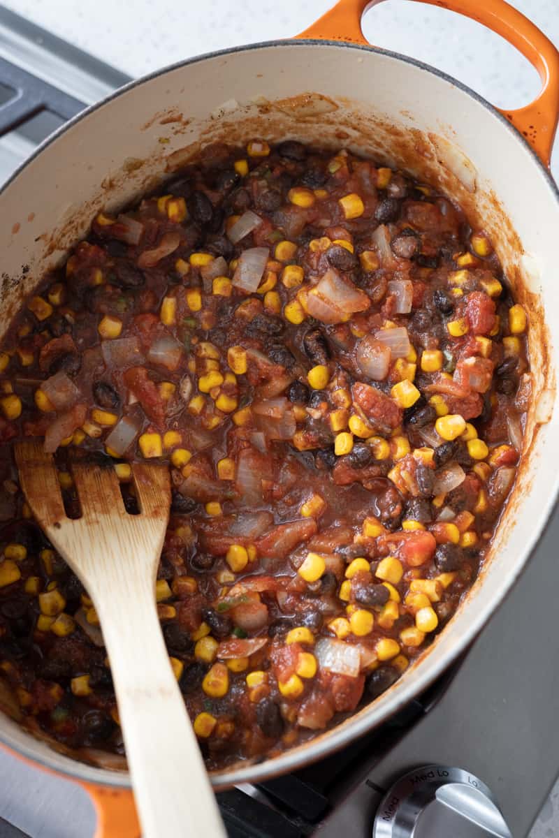 Jalapeño, tomatoes, corn, black beans, tomato paste and spices added to the Dutch oven. 