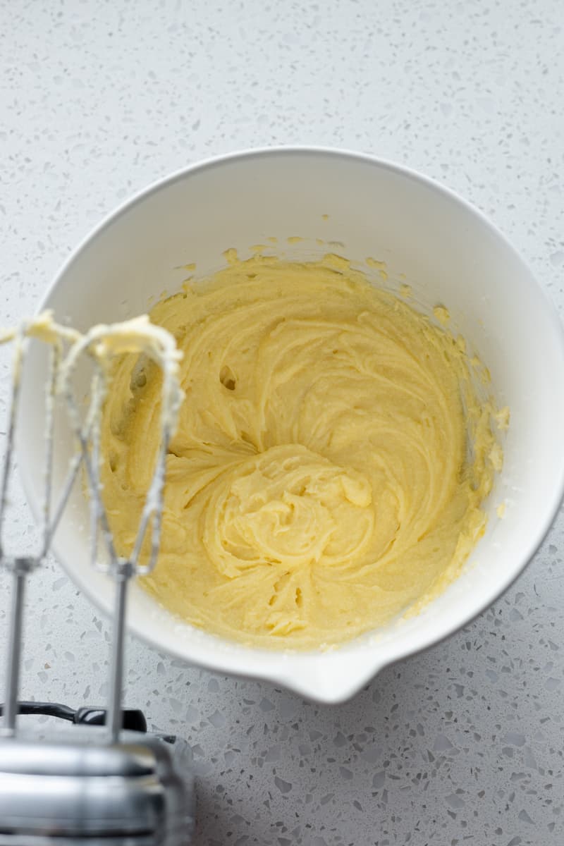 Batter in a white bowl with a handheld mixer. 