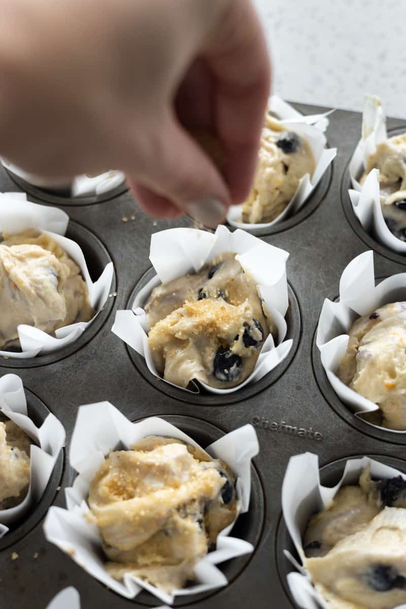 Hand sprinkling the batter with turbinado sugar before baking. 