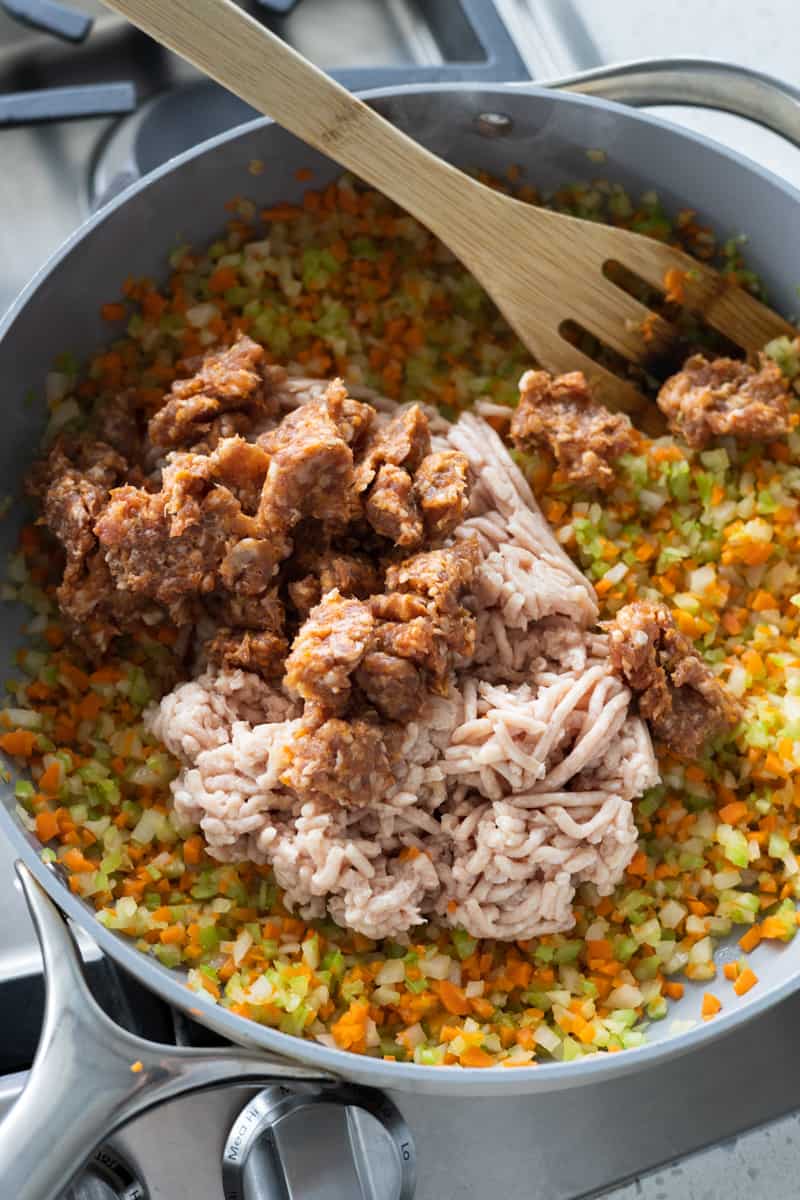 Meat added to the skillet of cooking veggies. 