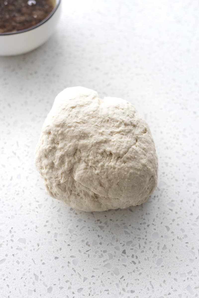 A ball of dough on the countertop. 