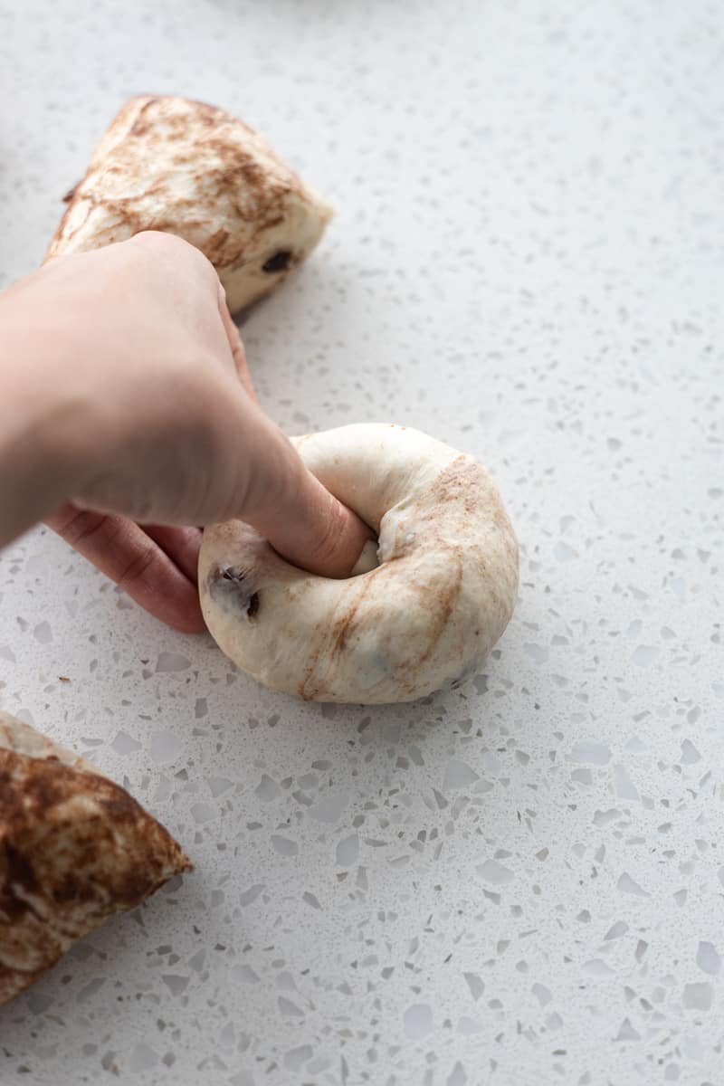 Thumb pressing a hole in the center of the dough ball. 