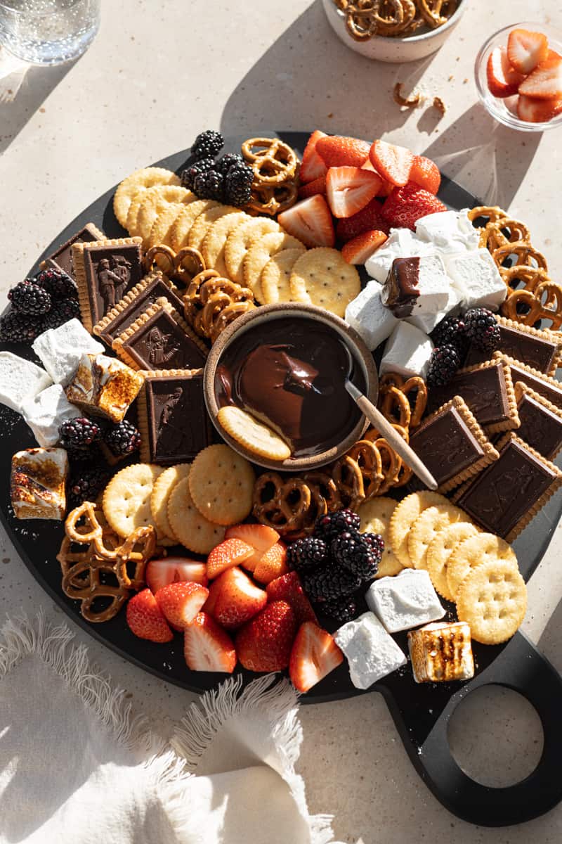 A full Dessert Charcuterie Board with a bowl of chocolate dipping sauce in the middle. 