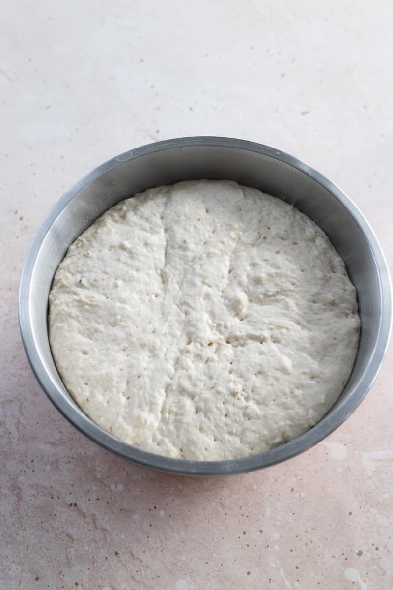 Dough after the first rise in a metal bowl.