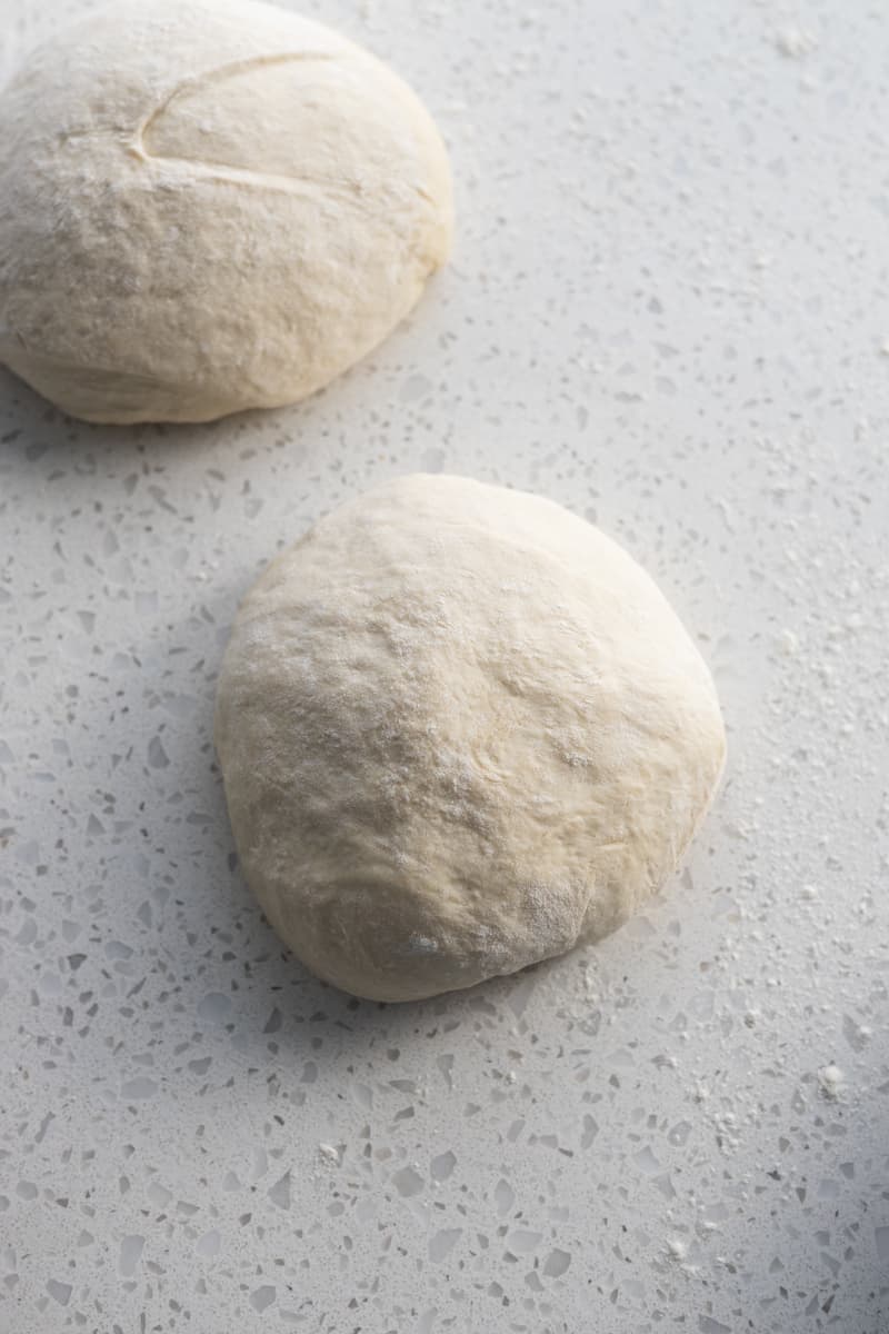 Sourdough discard pizza dough divided into two rounds.