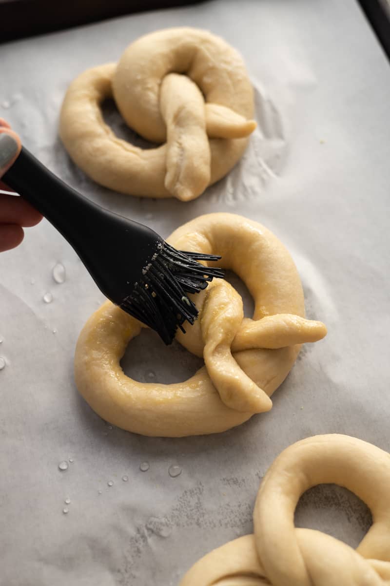 Pretzel being brushed with egg wash.