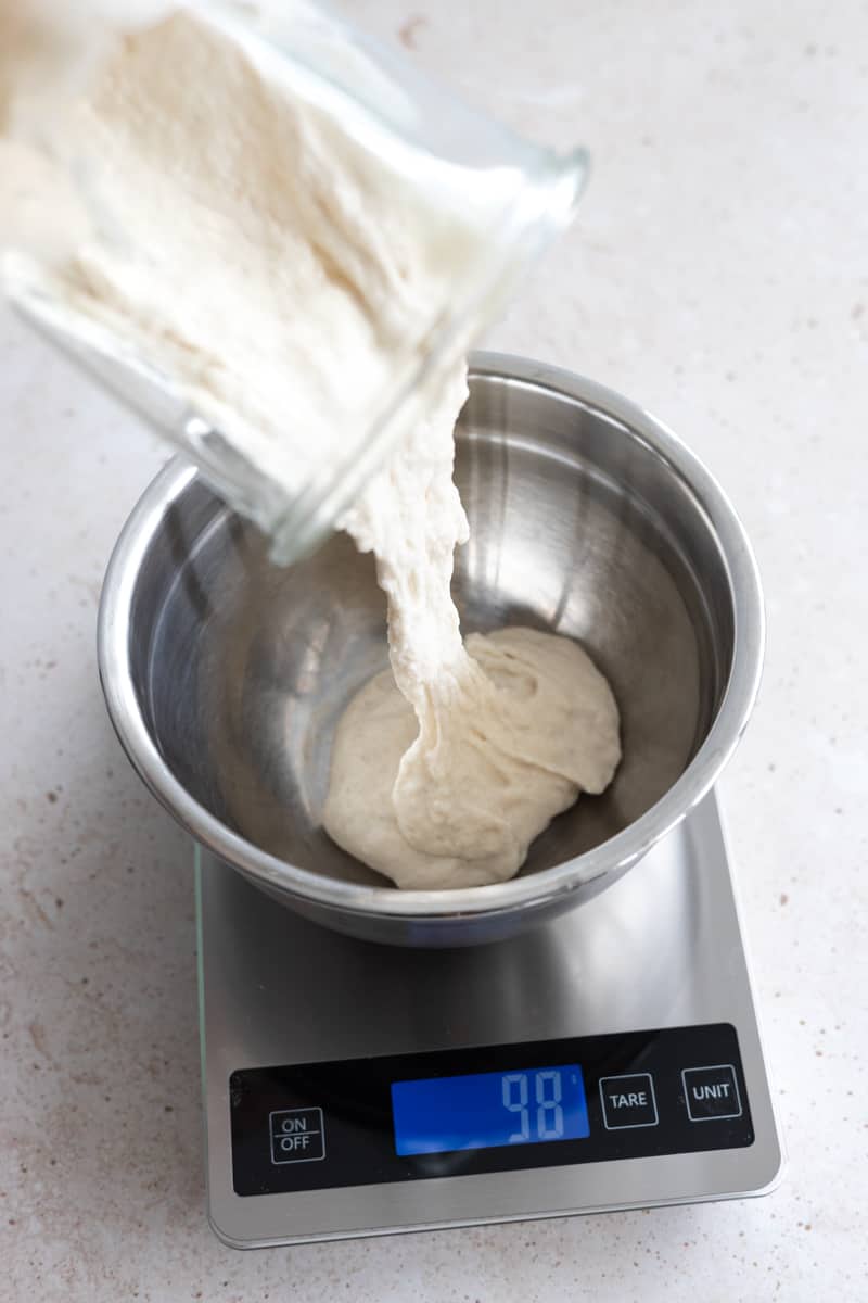 Measuring starter into a metal bowl on a kitchen scale. 