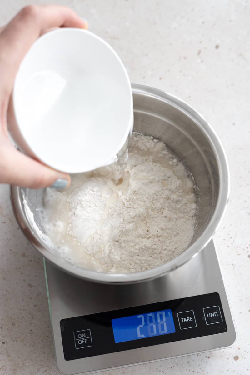 Water being added to the metal bowl on the kitchen scale. 