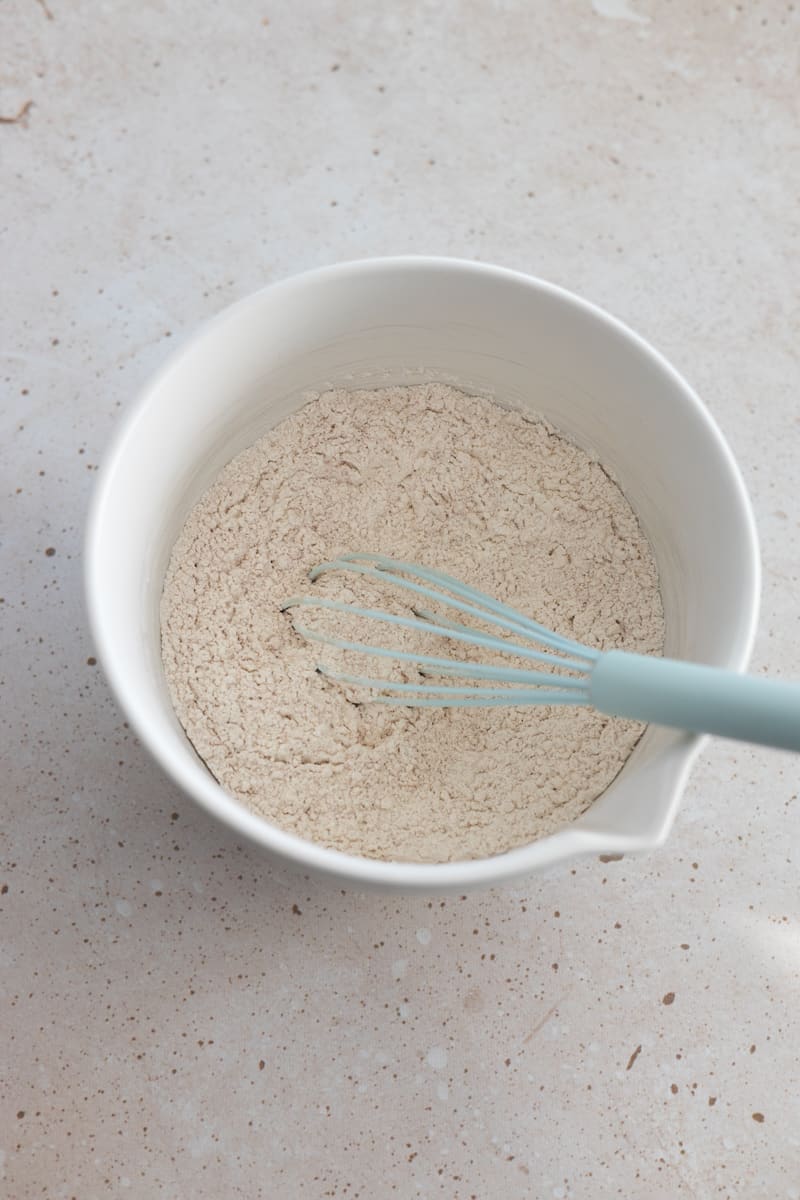Dry ingredients in a white bowl with a whisk.