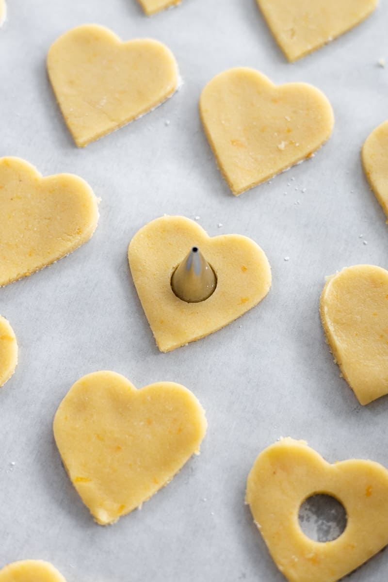 An icing piping tip pressed into the center of a heart-shaped cookie.