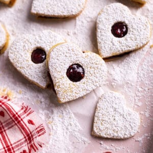 Heart Cookies with Jam stacked on a pink baking sheet.