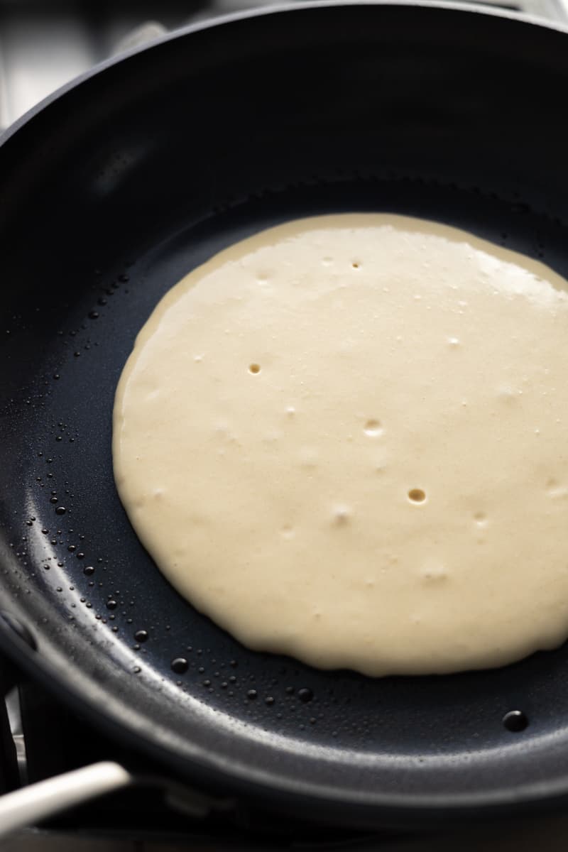 Batter starting to bubble in the skillet.