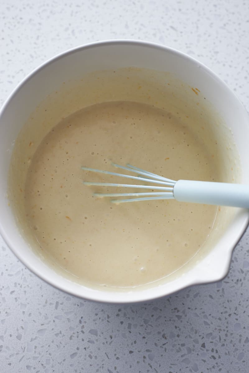 Batter in a large white bowl with a whisk.
